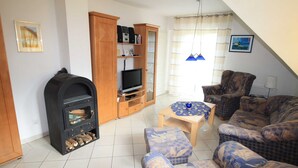 A living room with a fireplace, a television, and a sofa. - Apartment 2.4 - 55sqm with fireplace and 2 bedrooms - ADS apartments **approx. 20 (Ückeritz)