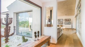 Ein modernes Interieur mit einer Holzbank, einer Glaswand und einem Essbereich mit einer Couch und einem Tisch.