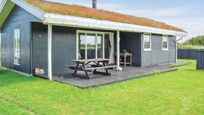 A small, single-story building with a sloped roof covered in grass, a wooden deck, and a picnic table. - Amazing home in Rømø with WiFi (Rømø)