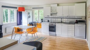 A modern kitchen with white cabinets, a built-in oven, and a microwave. There is a dining area with a table and chairs, and a window providing natural light. - Nice home in Långaryd with WiFi (Långaryd)