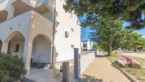 Ein Gebäude mit weißer Fassade, mehreren Bögen und einem gepflasterten Weg, der davor führt.