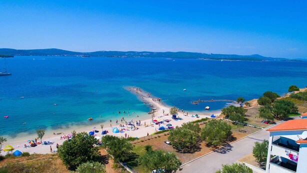 Ein Küstenstrand mit klarem Wasser, einem Sandufer und einigen Booten.