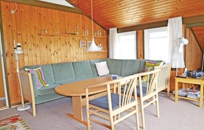 Relax in this inviting room with a sofa, table, and chairs, plus a shelf with decorative items and a radio.