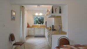 Une cuisine avec des meubles blancs, une fenêtre et un plan de travail sur lequel se trouvent divers objets.