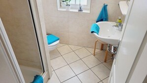 A bathroom with a toilet, sink, and shower. There is a window with a plant and a bird decoration. - (124) 2-room apartment beach road - Appartementhaus Residenz Strandstr. 31 (Kühlungsborn)