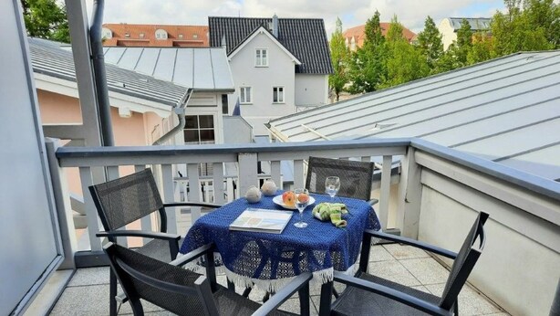 A balcony with a table and chairs, a glass of water, and a plate of food. - (124) 2-room apartment beach road - Appartementhaus Residenz Strandstr. 31 (Kühlungsborn)