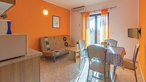 Un espacio habitable compacto con sofá, mesa de comedor, sillas y una pequeña zona de kitchenette.