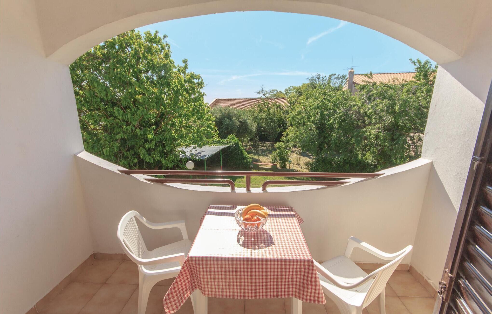 Een balkon met een tafel en stoelen, een geruit tafelkleed en een schaal met fruit.