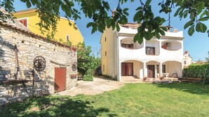 Un edificio de dos pisos con un muro de piedra y un edificio amarillo al fondo.