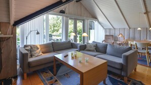 A spacious living room with a high ceiling, large windows, and a cozy seating area with a sofa and a coffee table.