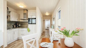 A modern kitchen with white cabinetry, a wooden countertop, and a dining area with a wooden table and chairs. - Lovely home in OstseeResort Olpenitz with sauna (OstseeResort Olpenitz)