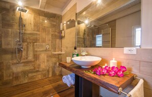 A modern bathroom with a wooden shower enclosure, a large vessel sink, and a mirror above the sink.
