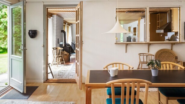 Een eetgedeelte met een houten tafel en stoelen, een groot raam en uitzicht op een tuin.