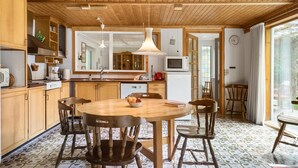 Een moderne keuken met houten kastjes, een ronde eettafel en een groot raam.