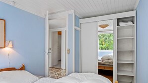 Een slaapkamer met een bed, een kledingkast en een deur naar een andere kamer.