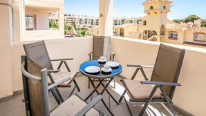A balcony with two chairs and a table, overlooking a residential area with a tower. - Nice apartment in Riviera del Sol (Riviera del Sol)