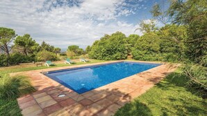 A rectangular swimming pool with a tiled deck, surrounded by lush greenery and trees. - Beautiful home in Capmany (Capmany)