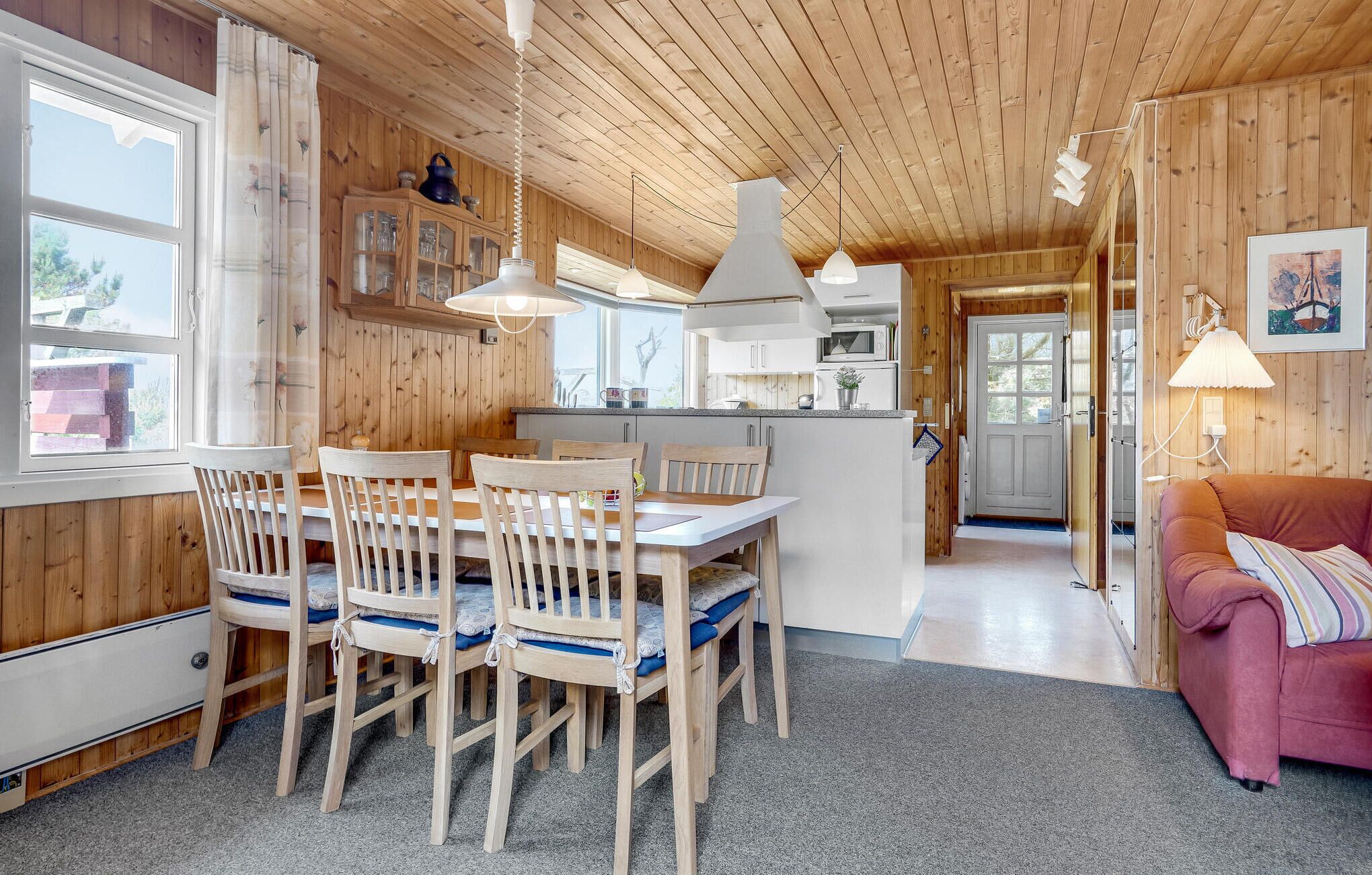 Interior acogedor de una cabaña con comedor de madera, cocina y sala de estar con sofá.
