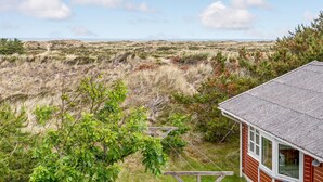 A red building with a white window, surrounded by a grassy landscape and trees. - Cozy home in Frøstrup with sauna (Frøstrup)