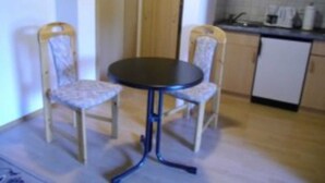 A small kitchen with a round table and two chairs, a refrigerator, and a microwave. - Double room 8 - Budach: Country vacation at the gates of Flensburg (Handewitt)