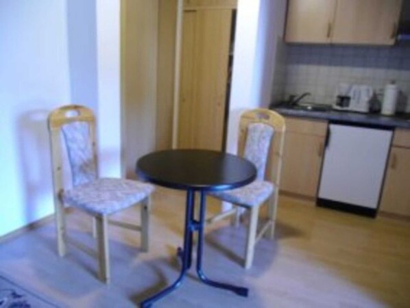 Une petite cuisine avec une table ronde et deux chaises, un réfrigérateur et un four à micro-ondes.
