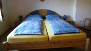 A double bed with a wooden frame, two pillows, and a wall-mounted fan. - Double room 8 - Budach: Country vacation at the gates of Flensburg (Handewitt)