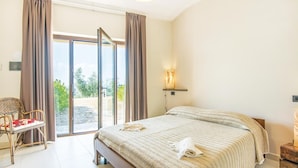 A hotel room with a bed, a chair, a table, and a view through the glass doors. - Lovely home in Collevecchio (RI) with sauna (Collevecchio (RI))