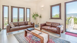 A spacious living room with two leather sofas, a coffee table, and a large window offering a view of the countryside. - Lovely home in Collevecchio (RI) with sauna (Collevecchio (RI))