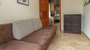 A living room with a brown sofa, a wooden cabinet, and a kitchen visible through an open door. - Residence Seestern Whg S-01 ..-See-01 (Kühlungsborn)