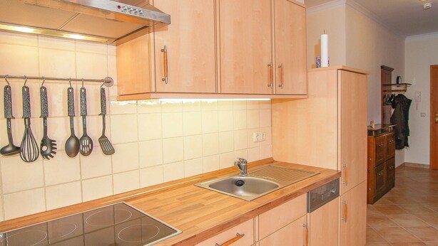 A kitchen with wooden cabinets, a stainless steel sink, and a range hood. - Residence Seestern Whg S-01 ..-See-01 (Kühlungsborn)