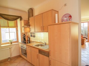 Une cuisine avec des meubles de rangement en bois, une cuisinière et un évier.