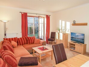 Un salon comprenant un canapé, une table basse, un meuble pour la télévision et un fauteuil.