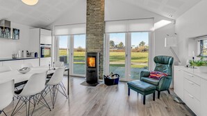 Una cocina moderna con un ventanal grande, una chimenea y un comedor con sillas blancas.