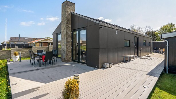 Una casa moderna con una terraza amplia, una chimenea y un ventanal de vidrio que da a un patio.