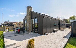 Una casa moderna amb un gran terrat, una xemenea i una porta de vidre que dona a un pati.