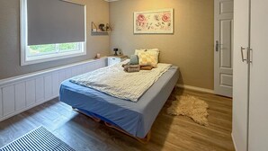 A bedroom with a bed, a window, a radiator, a door, and a wall-mounted shelf with a floral picture. - 5 bedroom amazing home in Matre (Matre)