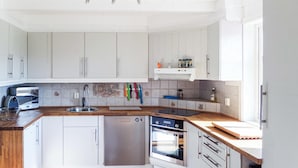 A modern kitchen with white cabinetry, stainless steel appliances, and a wooden countertop. - 5 bedroom amazing home in Matre (Matre)