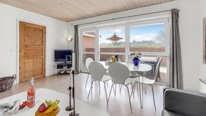 Ein modernes Wohnzimmer mit Fernseher, Esstisch und Stühlen.