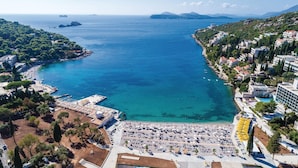 An aerial view of a coastal town with a beach, a marina, and residential buildings.
