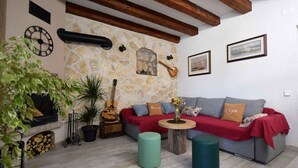 A cozy living room with a stone wall, a fireplace, a sofa, and a guitar.