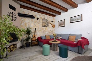 A cozy living room with a stone wall, a fireplace, a sofa, and a guitar.