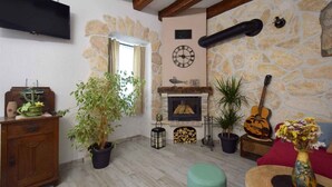 A living room with a stone wall, a fireplace, a clock, and a guitar.