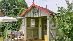Un petit bâtiment d’un seul étage, avec un toit rouge et une grande horloge sur la façade.