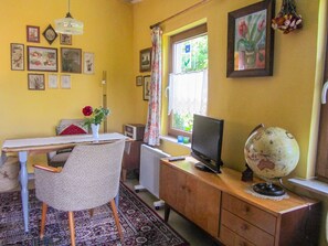 Una habitación con escritorio, silla, un globo terráqueo y varias fotografías enmarcadas en la pared.