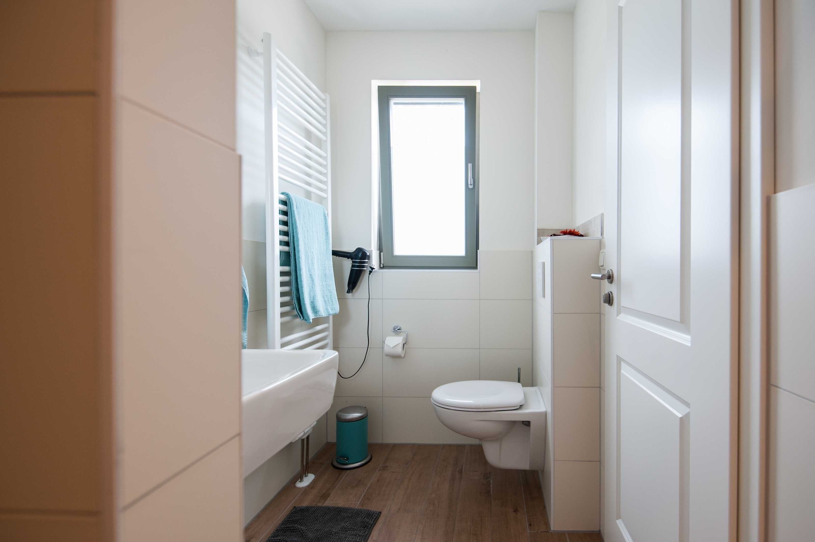 A compact bathroom with a toilet, sink, and window.