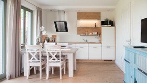 Eine moderne Küche mit weißen Schränken, einem Holztisch und einem blauen Schrank.
