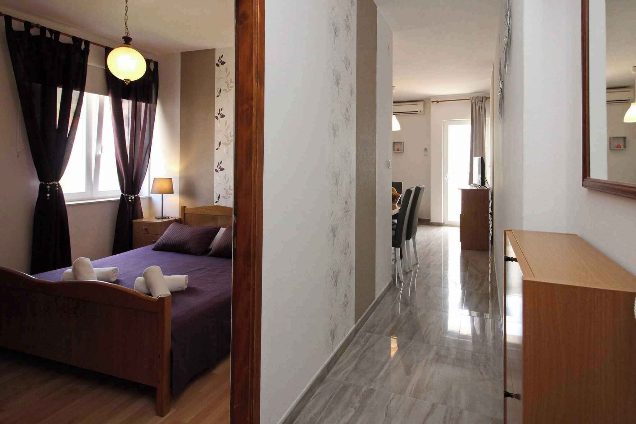A hotel room with a wooden bed, a nightstand, a lamp, and a large mirror.