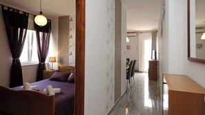 A hotel room with a wooden bed, a nightstand, a lamp, and a large mirror. - Holiday apartment with balcony and air conditioning (Baška)
