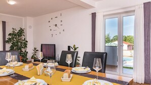 Un comedor con una mesa dispuesta para cuatro personas, un reloj en la pared y vistas a una piscina exterior.