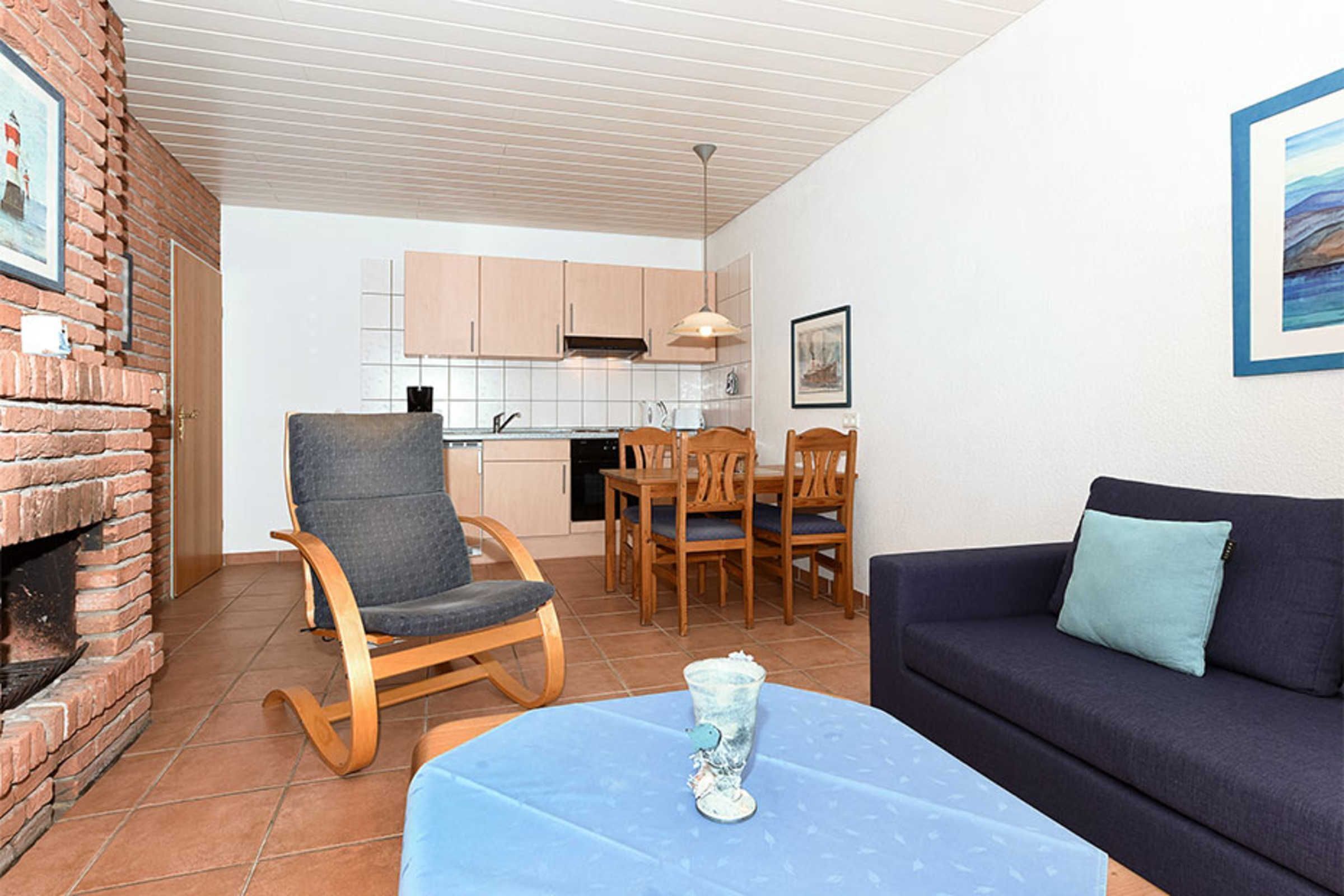 Ein Wohnzimmer mit einem blauen Tisch, einem dunklen Sofa, einem Holzschaukelstuhl und einem Kamin aus Ziegelsteinen.